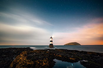 white, brown, lighthouse, remote, sky, clouds, sunset, rocks, rocky, sea, ocean