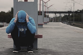 person, blue, adidas zip-up hoodie, sitting, post, daytime, Adidas, train station, station, man, fear