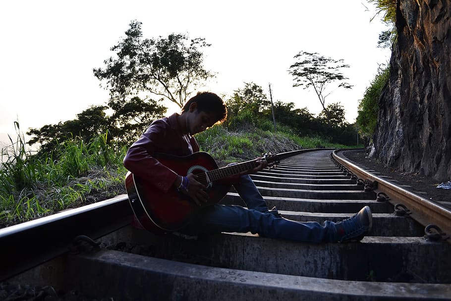 man, playing, guitar, sitting, train rail, daytime, railroad, guitarist, boy, pose, scene
