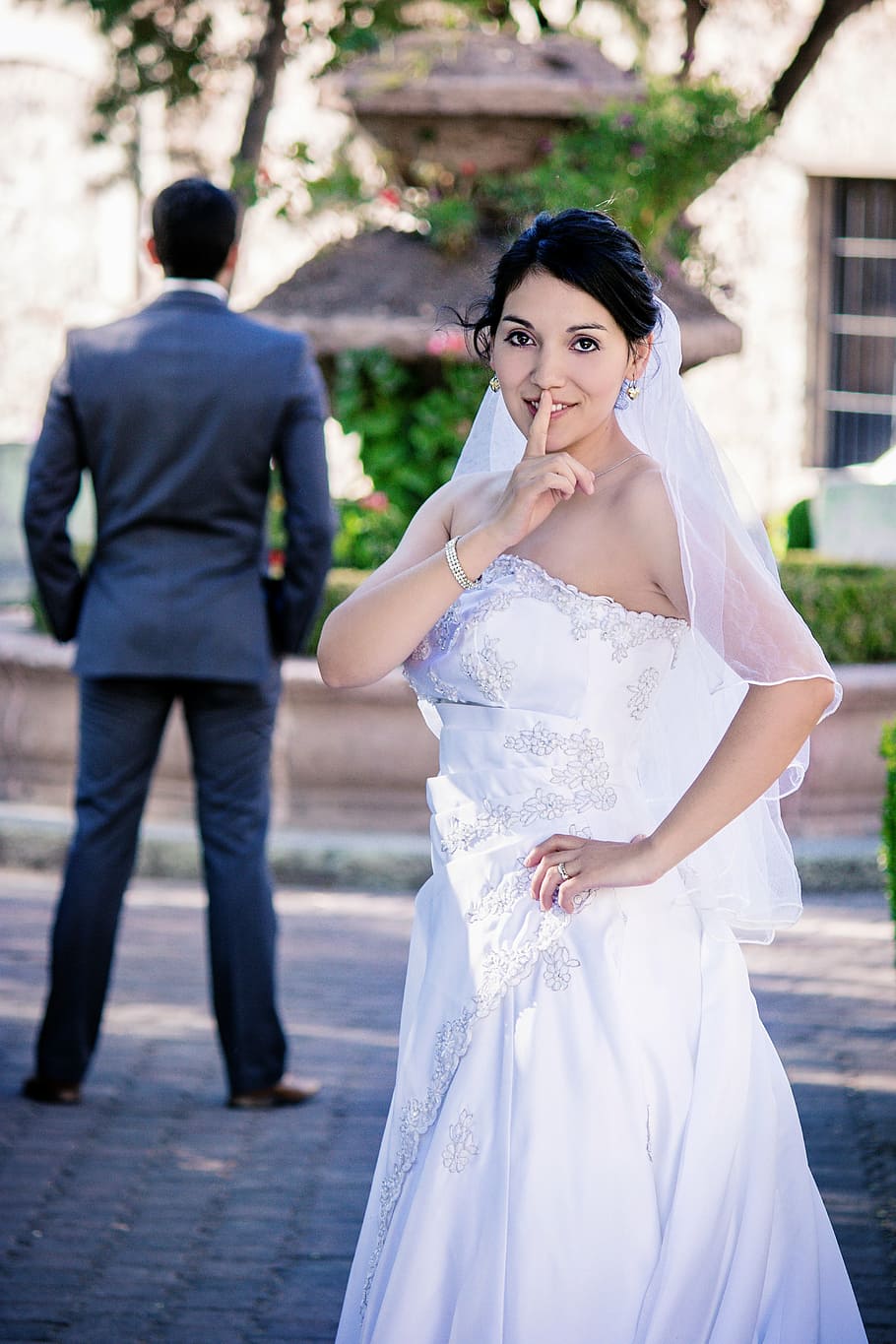 woman, white, strapless wedding gown, showing, silence gesture, sneaky, bride, finger, girl, groom, guy