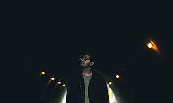 man, black, jacket, wearing, eyeglasses, standing, brown, sconce, dark, tunnel, lights