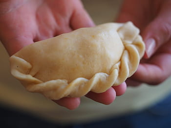 Person hält Gebäck, empanada, Spritzbeutel, Lebensmittel, Essen, intracorneal, gefüllt, menschliches Körperteil, Essen und Trinken, menschliche Hand, Nahansicht