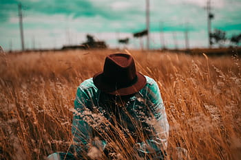person, sitting, wheat field, brown, hat, teal, sports, shirt, withered, leaf, field