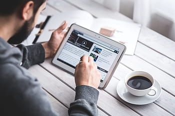 man, wearing, gray, sweater, using, white, tablet computer, cup, filled, black, coffee