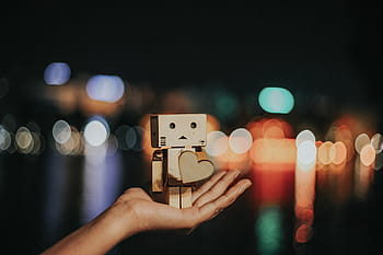 person, holding, brown, wood, carving, shallow, focus photography, wooden, robot, shape, heart