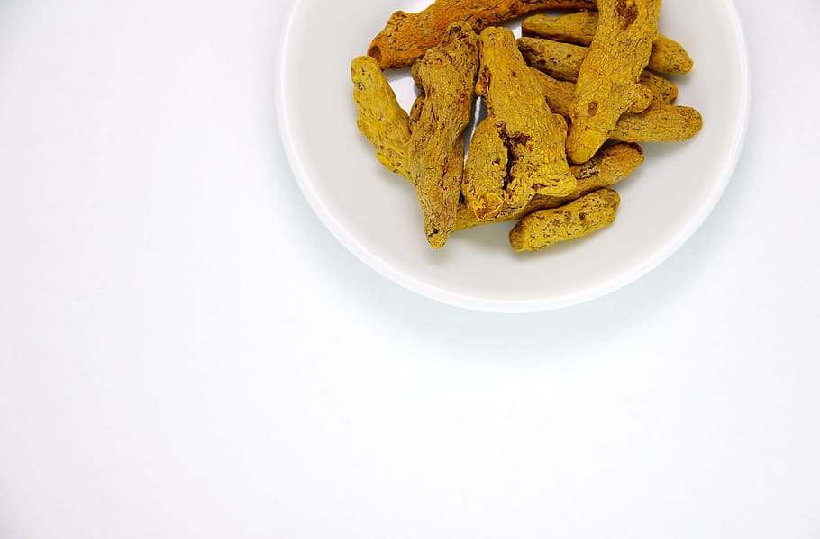 dish in plate, turmeric, dried rhizomes, health food, white dish, white background