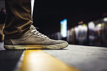 selective, focus photo, person, wearing, gray, white, suede low-top shoe, brown, jeans, yellow, concrete