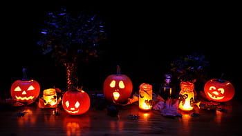 turned on jack-o-lanterns, dark, decoration, fall, glow, glowing, halloween, illuminated, lantern, leaves, lights