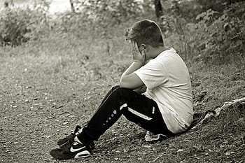 grayscale photo, man, holding, face, sitting, grass field, boy, child, sad, alone, sit