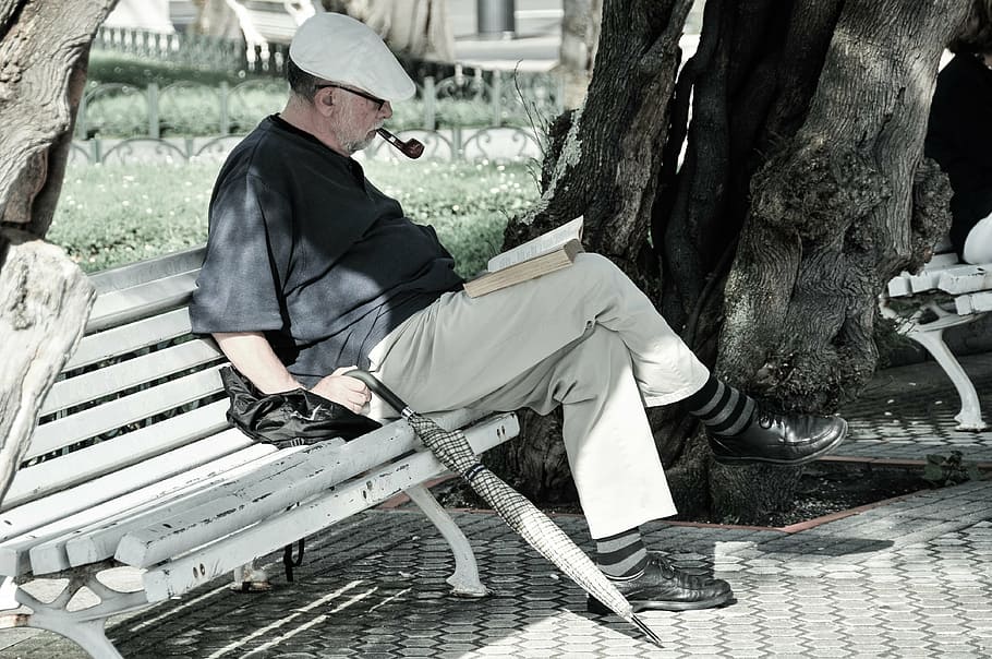 man, black, shirt, sitting, bench reading book, reading, park, pipe, umbrella, peaceful, person