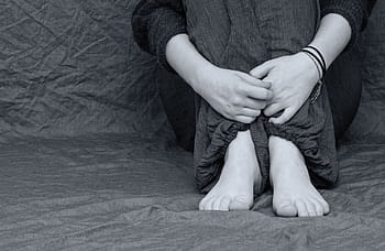 grayscale photo person, wears, pants, long-sleeved, shirt, desperate, sad, depressed, feet, hands, folded
