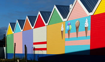 色とりどりの家、 昼間のシーン、 カラフルな建築、 活気のある建物、 アイスクリームの壁画、 塗られた家、 明るい色、 屋外設定、 晴れの日、 住宅街、 芸術的なデザイン