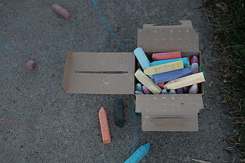 assorted-color chalks, brown, cardboard box, assorted, chalks, box, chalk, crayons, pavement, drawing, high angle view