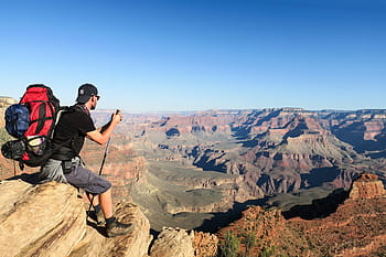 man, carrying, hiking, backpack, top, mountain, sitting, brown, rock, daytime, nature